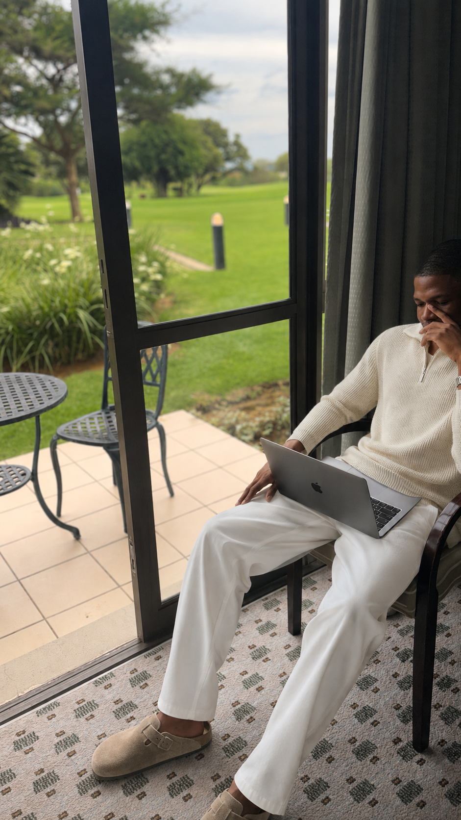 KD, founder of CopyKD, sitting beside a window with a MacBook